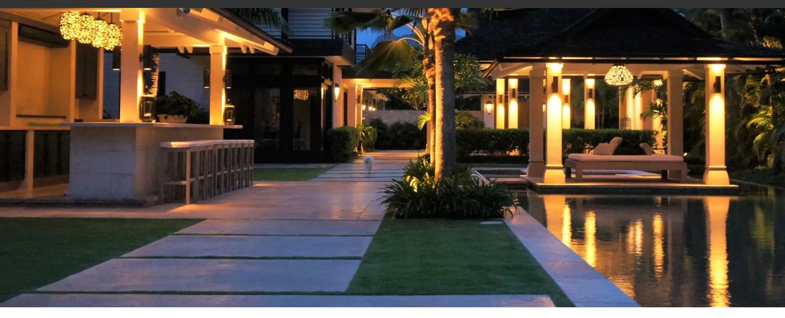 Copper and brass pendant lighting glowing over a lit walkway at a private Hawaii residence at dusk